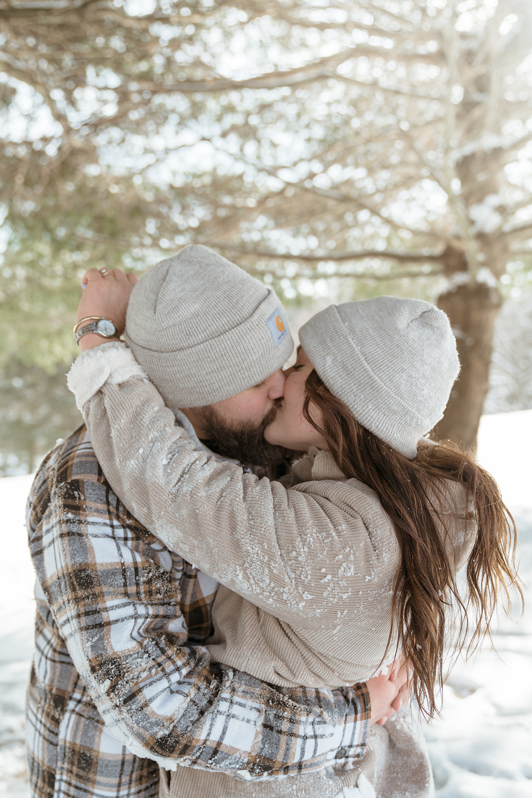 Couple kisses under snow covered pine trees