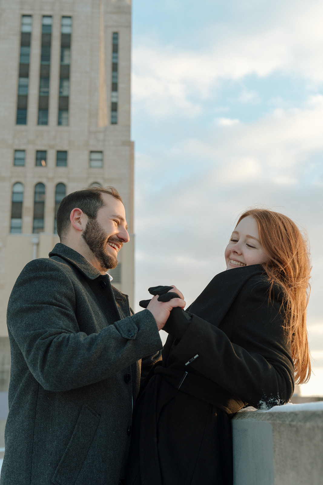 Couple holds hands during winter engagement session on top of parking garage at sunset in downtown Columbus, Ohio