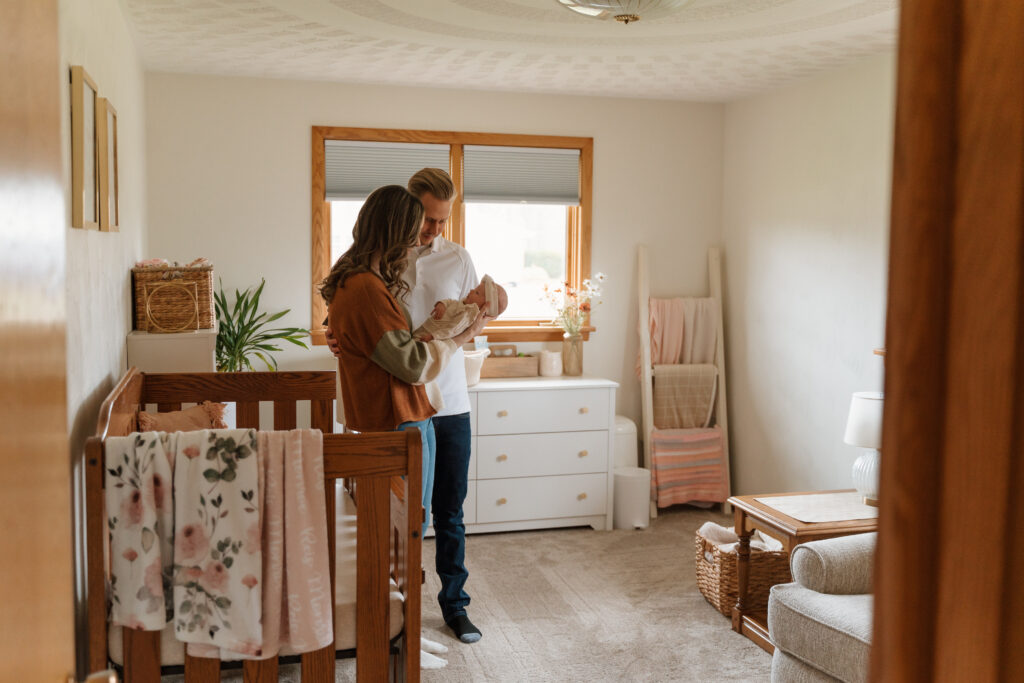 New parents hold baby girl in nursery during in home newborn session