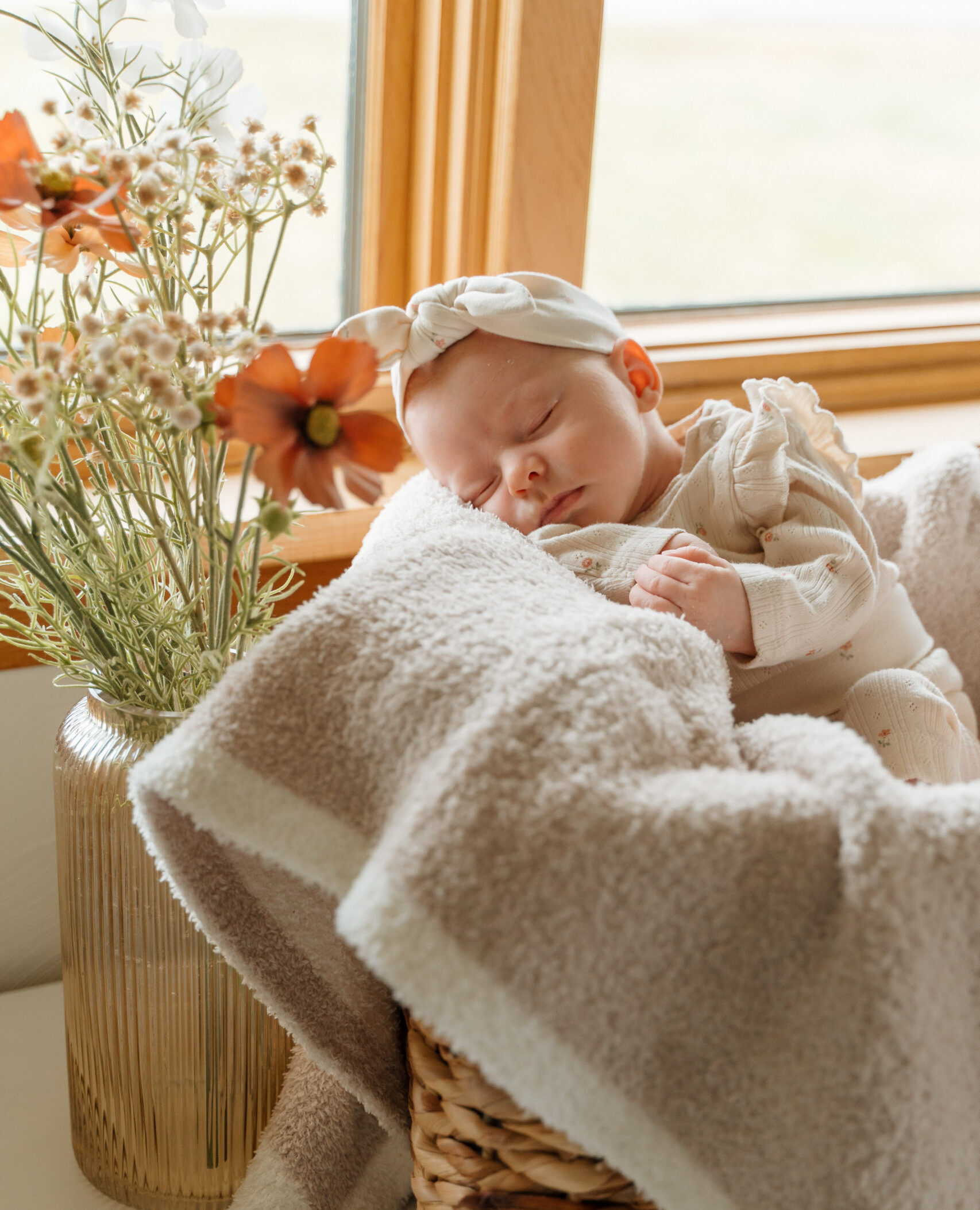 Newborn baby laying in the window with a jar full of flowers during in home newborn photo session